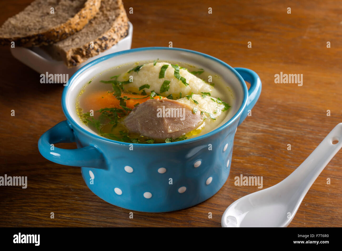 Zuppa di pollo con gnocchi di pane e in blu ciotola sul tavolo di legno Foto Stock