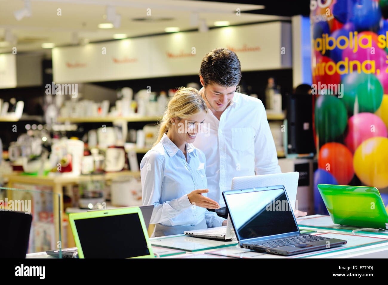Coppia giovane nel negozio di elettronica di consumo guardando ultimo laptop, televisione e foto fotocamera Foto Stock