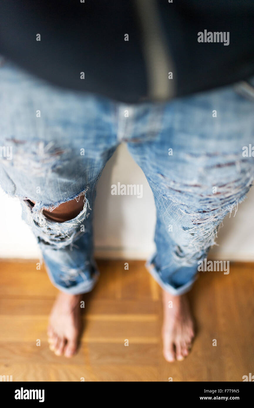 Giovane ragazza nel quartiere alla moda di jeans strappati con fori, Germania Foto Stock