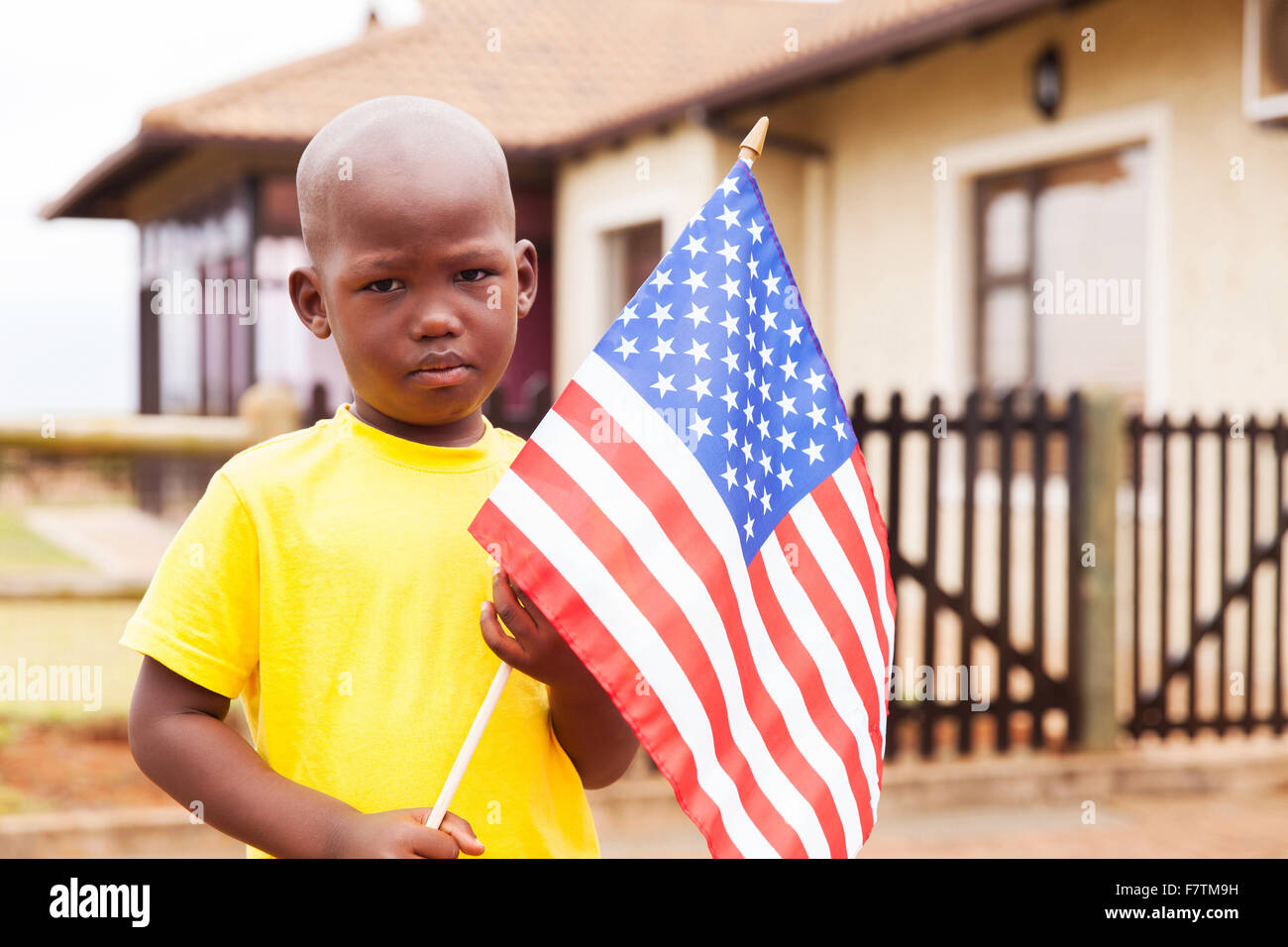 Ritratto di adorabili poco boy holding bandiera americana davanti a casa Foto Stock