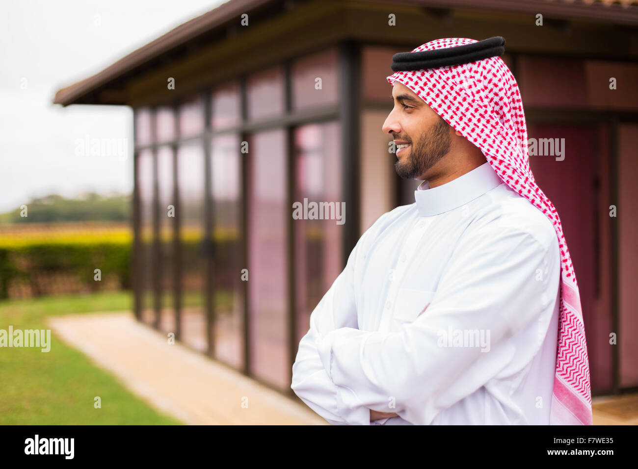Riflessivo Arabian uomo in piedi di fronte a casa sua Foto Stock