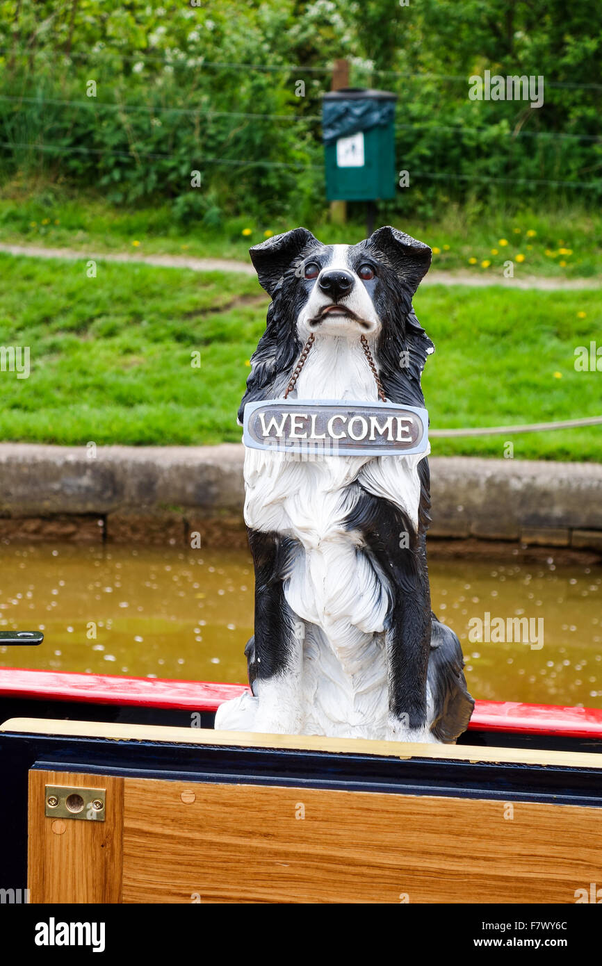 Un modello di plastica di un Border Collie cane con un segno intorno il collo dicendo 'Welcome' su una piccola barca o Inclus. Foto Stock