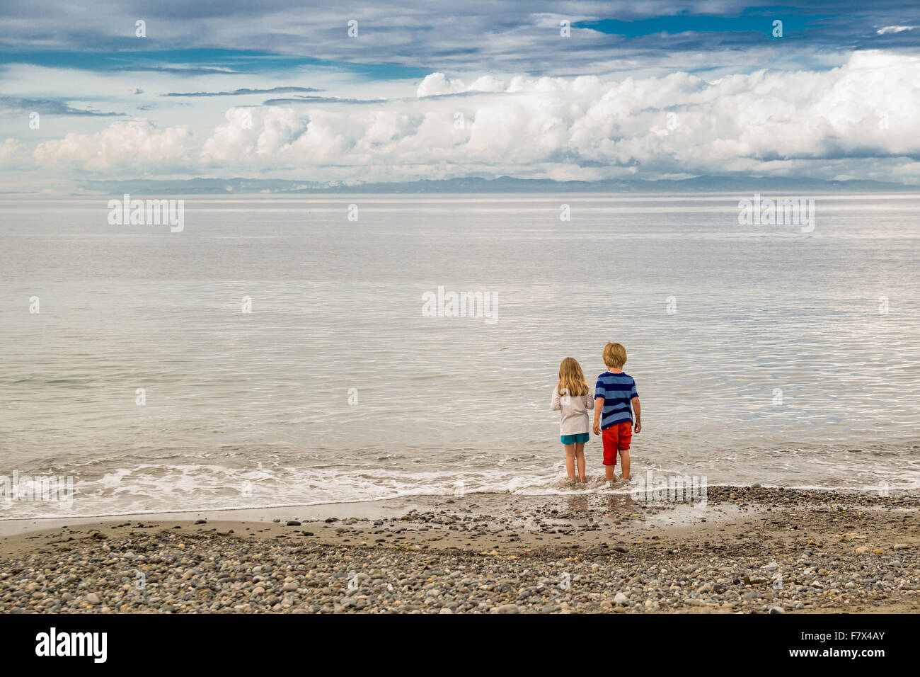 Vista posteriore del ragazzo e una ragazza in piedi sulla spiaggia Foto Stock