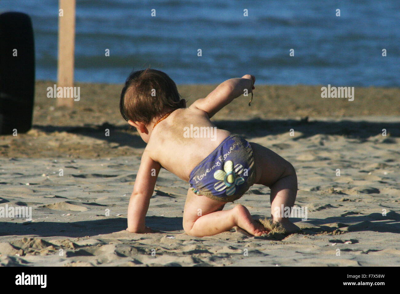 Baby strisciando sulla spiaggia, Senigallia Italia Foto Stock