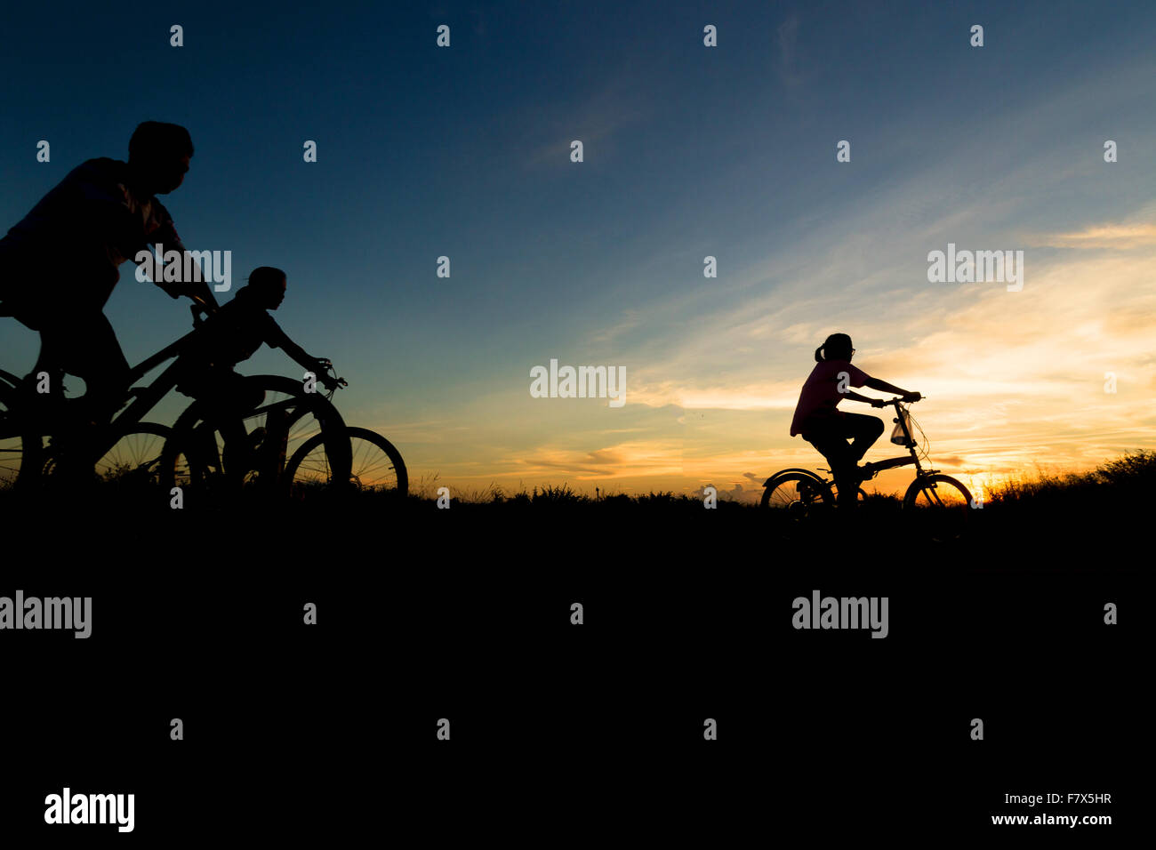 Silhouette di famiglia escursioni in bicicletta al tramonto Foto Stock