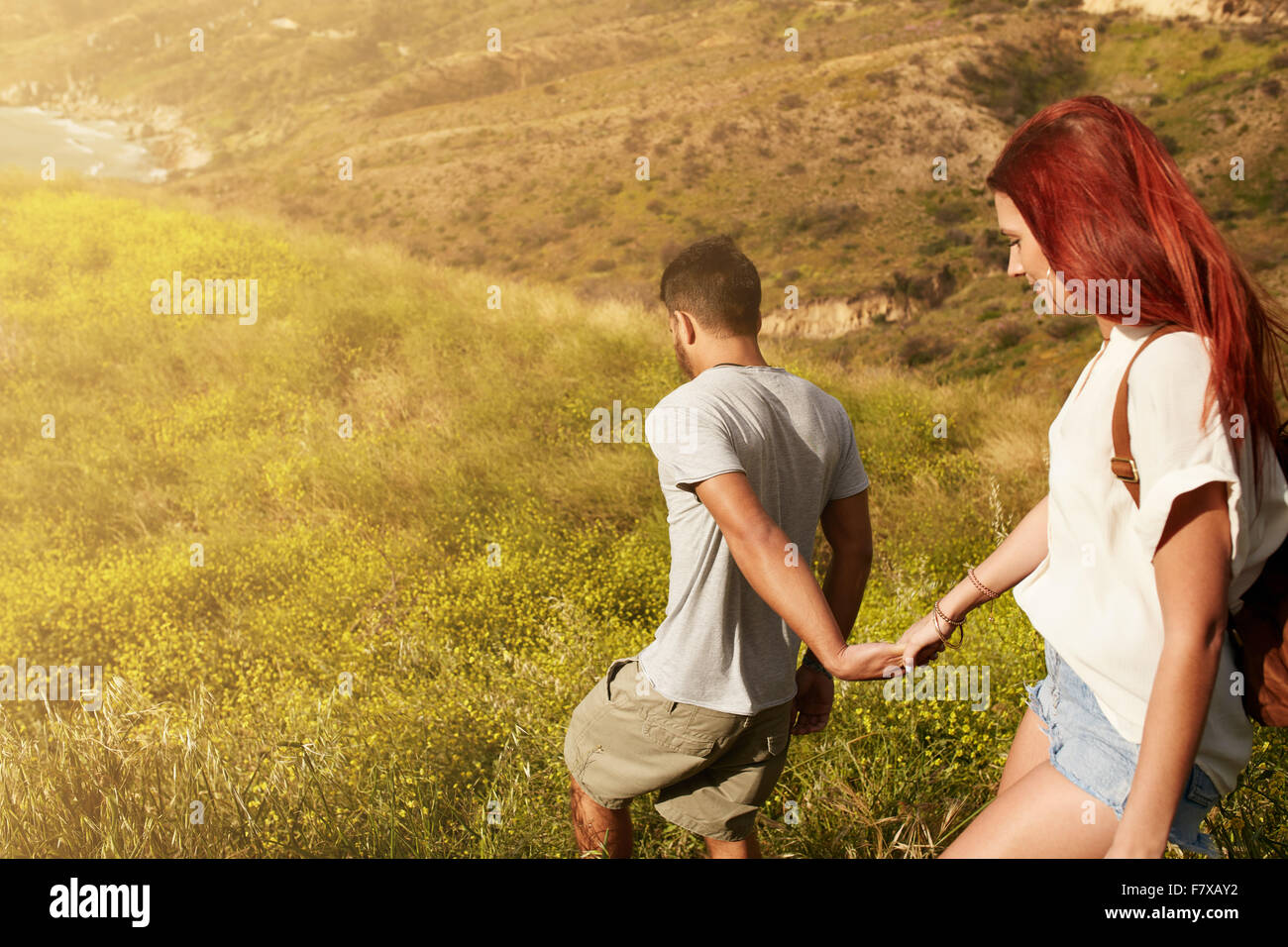 Colpo all'aperto di coppia giovane godendo sulla loro vacanza, percorrendo a piedi un picco tenendo le mani. Coppia caucasica escursionismo su un estate Foto Stock