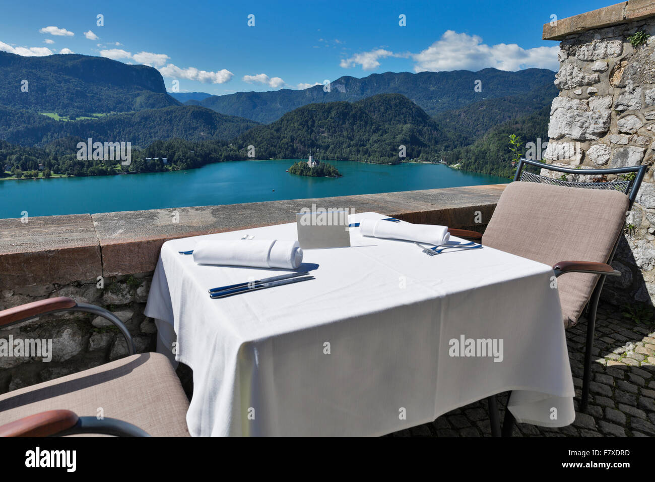 Tabella servito con piastra emty all'aperto. Vista sul lago di Bled, isola con la Chiesa e con le montagne delle Alpi in background. La Slovenia. Foto Stock