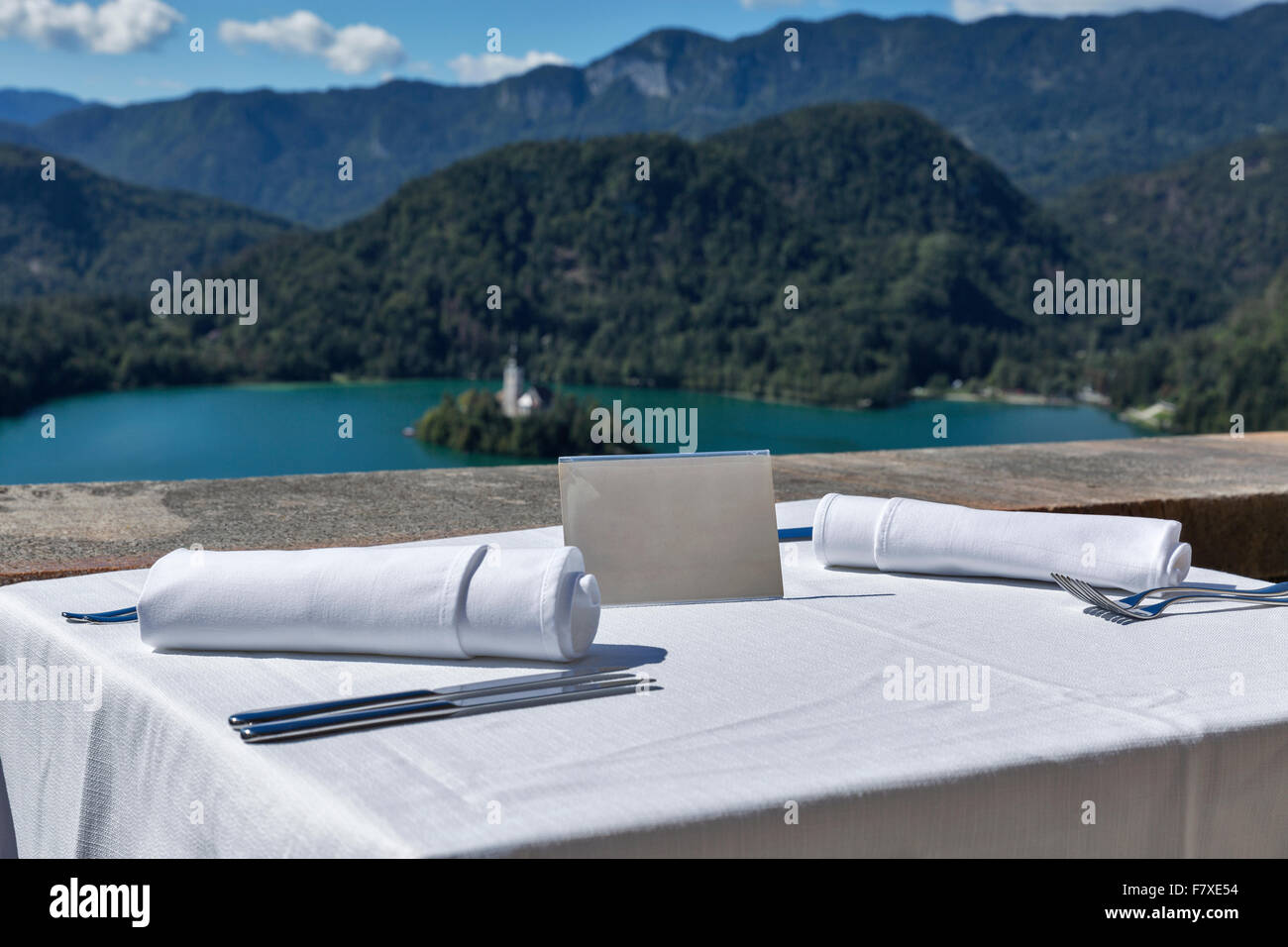 Tabella servito con piastra vuota all'aperto. Vista sul lago di Bled, isola con la Chiesa e con le montagne delle Alpi in background. La Slovenia. Foto Stock