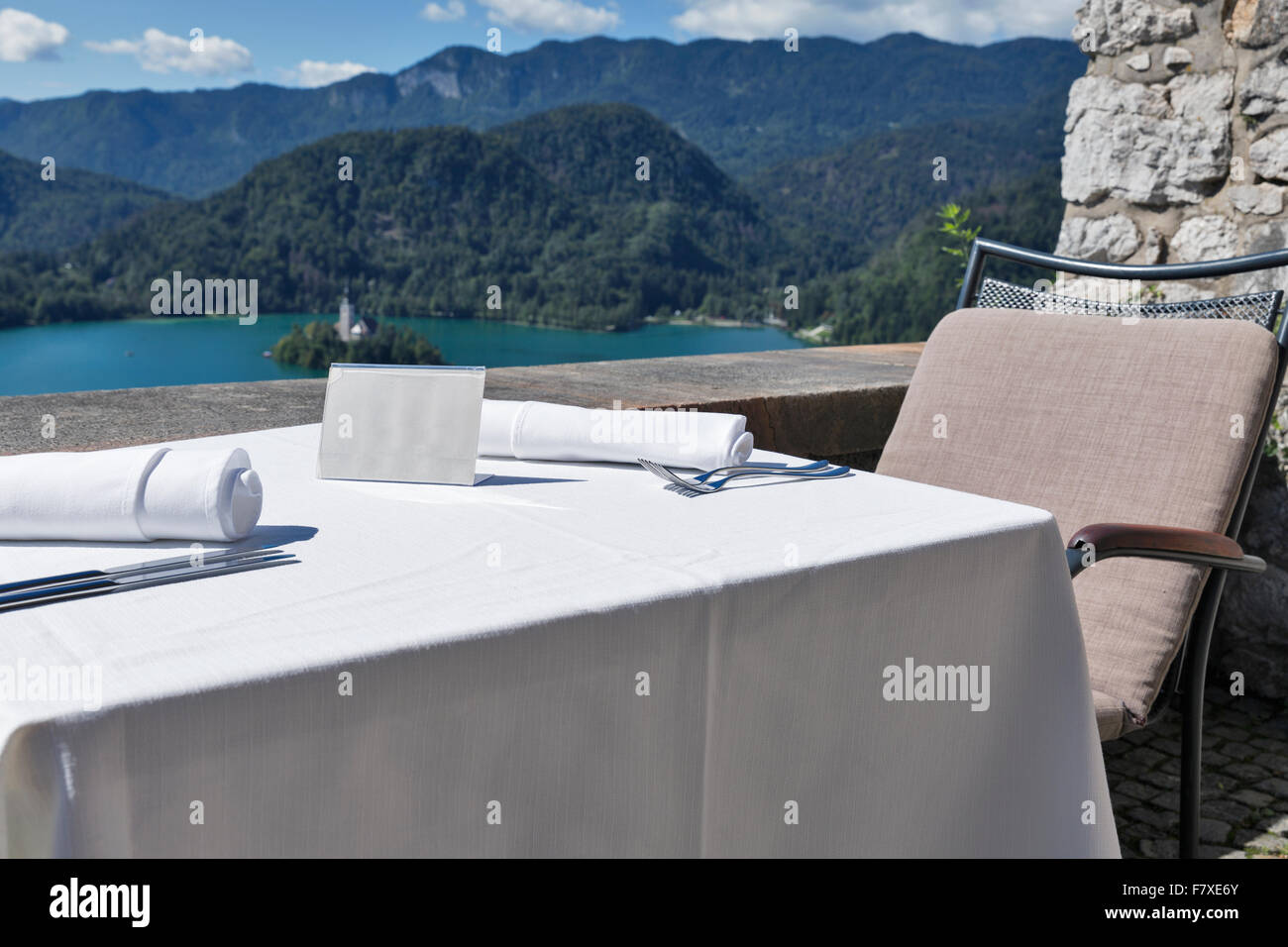 Tabella servito con piastra vuota all'aperto. Vista sul lago di Bled, isola con la Chiesa e con le montagne delle Alpi in background. La Slovenia. B Foto Stock