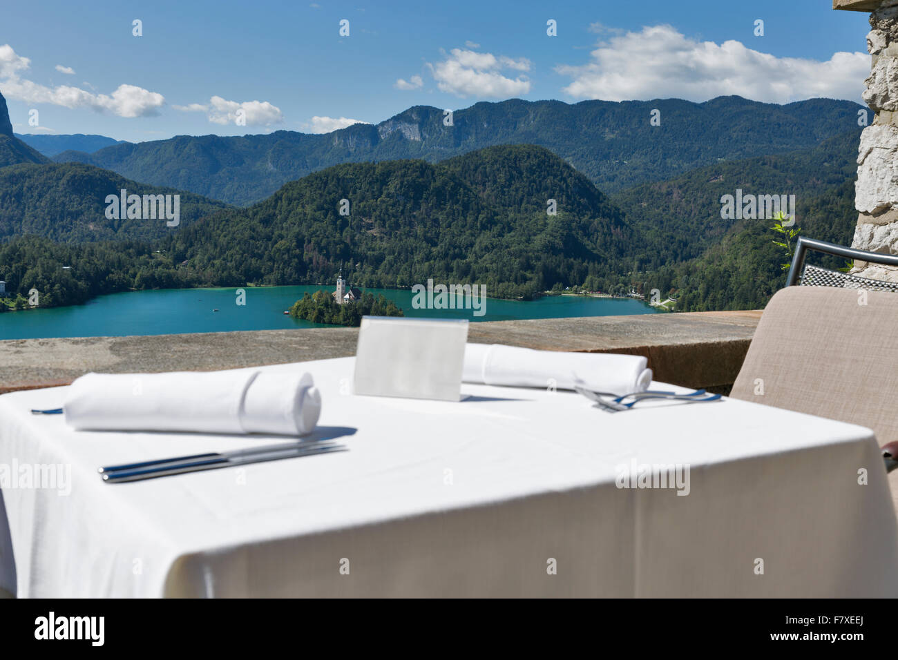 Tabella servito con piastra vuota all'aperto. Vista sul lago di Bled, isola con la Chiesa e con le montagne delle Alpi in background. La Slovenia. F Foto Stock