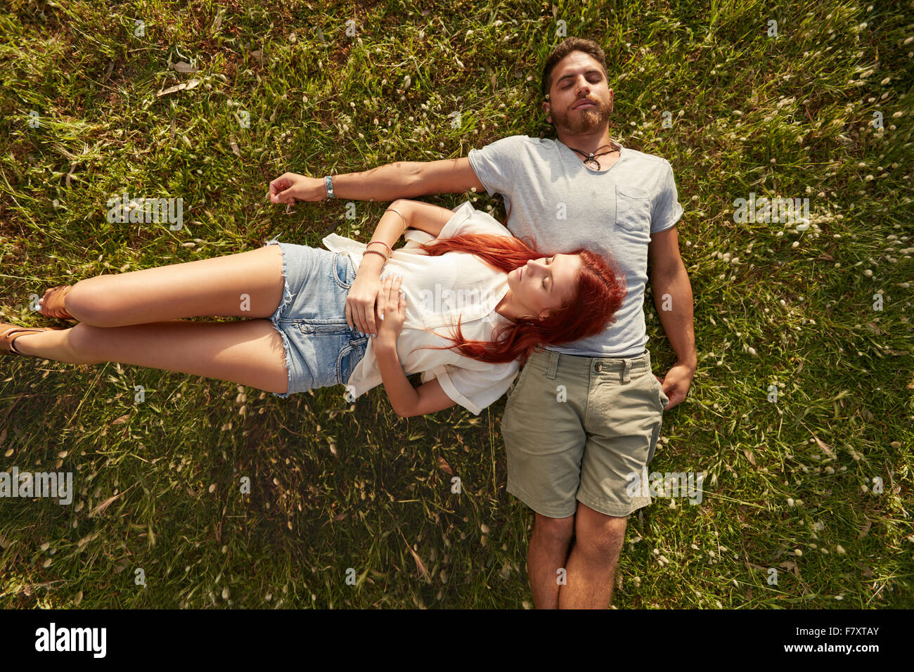 Giovane uomo e donna sdraiata sul prato dormire. Vista aerea della coppia giovane appoggiato insieme sull'erba. Foto Stock