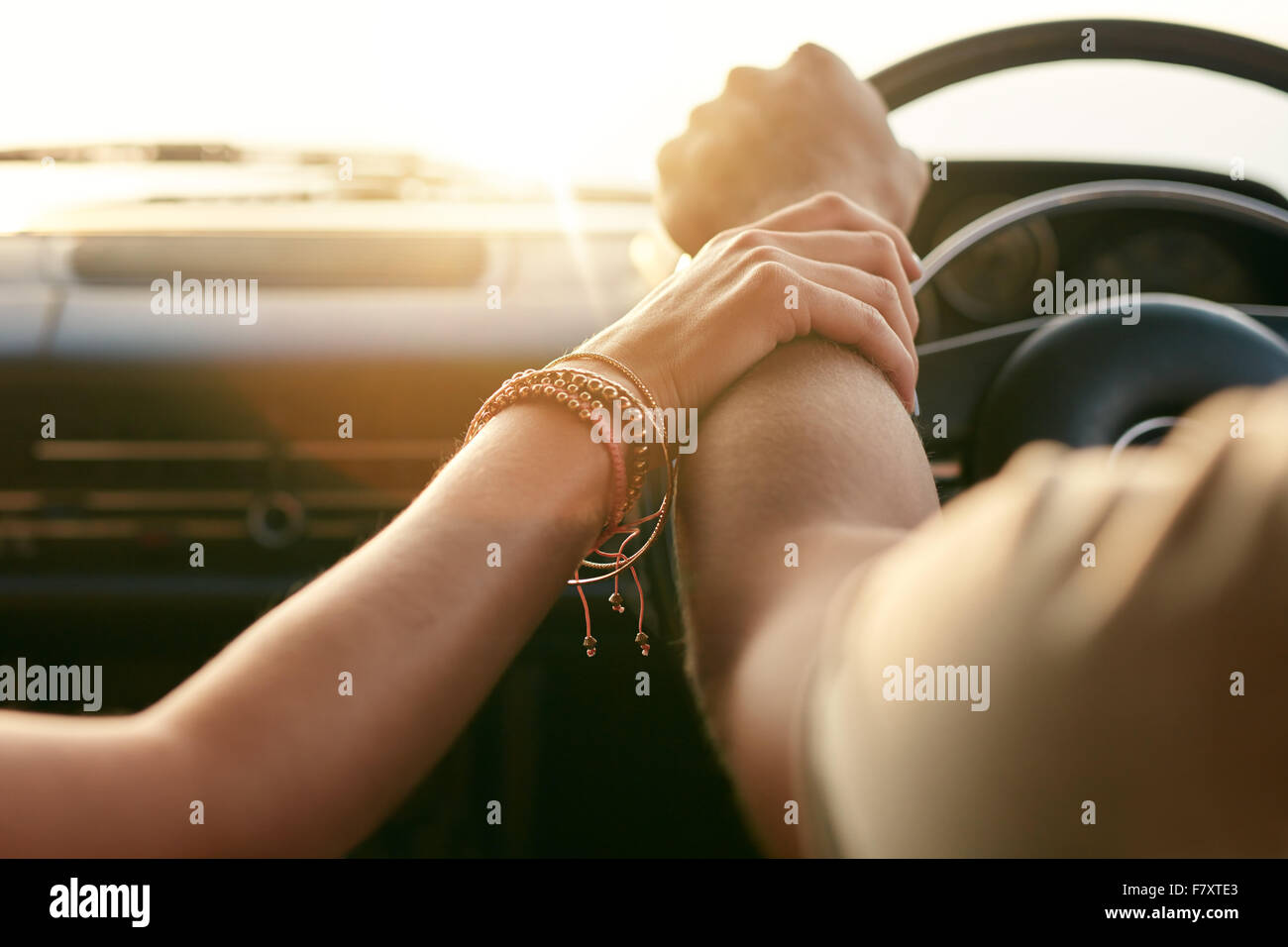 Immagine ravvicinata di amare giovane che viaggiano in auto e tenendo le mani. Focus sulle mani di un uomo e di una donna in un viaggio su strada. Foto Stock