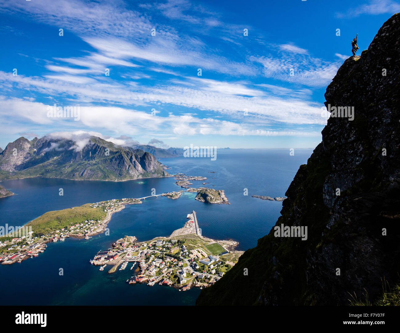 Un scalatore saluta la vista e celebra la sua ascesa alla vetta del Reinebringen sopra Reine = western Isole Lofoten in Norvegia Foto Stock