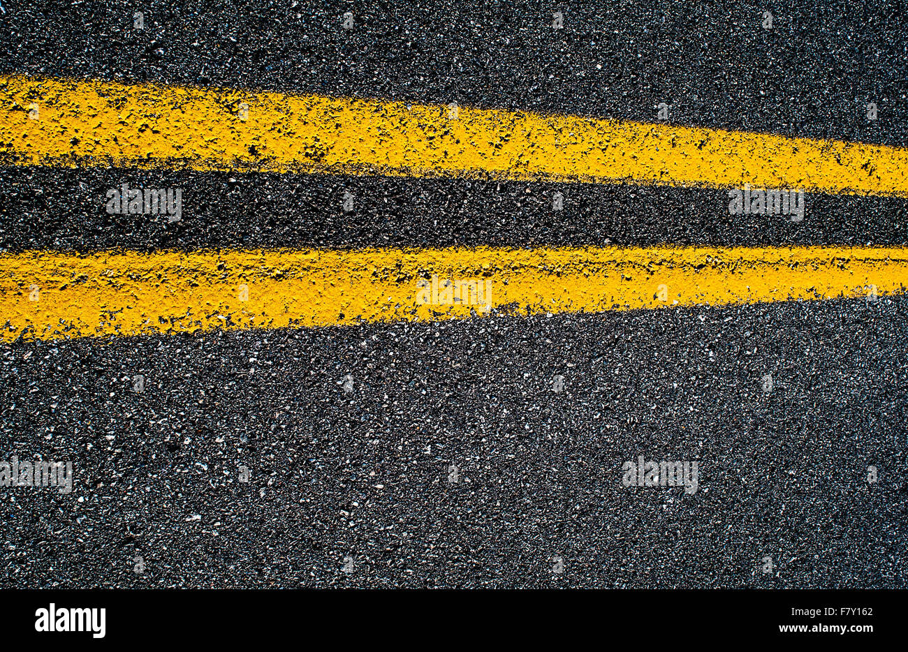 Primo piano di una doppia linea gialla su una strada asfaltata, orizzontale. Foto Stock