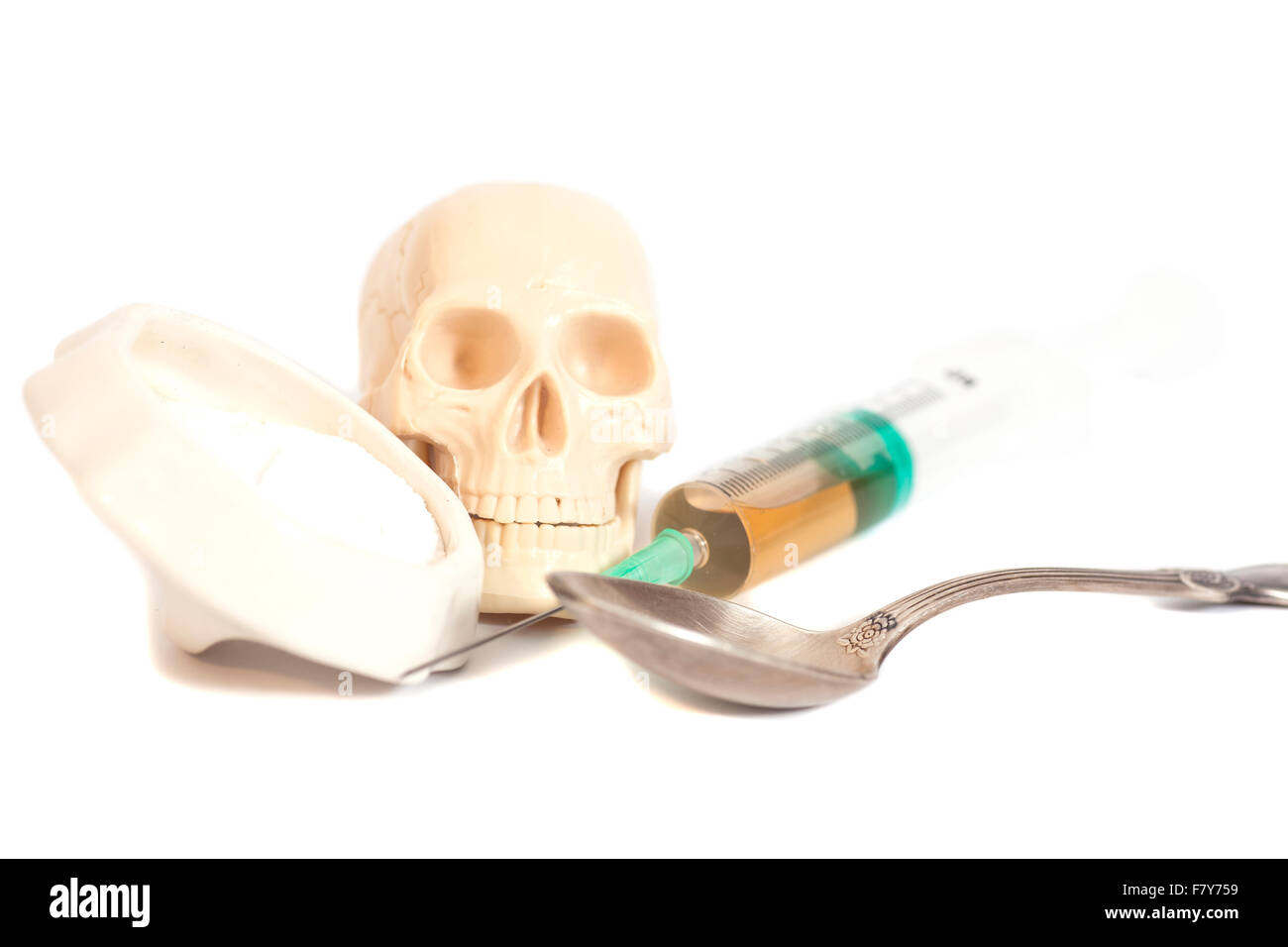 Il cranio e la siringa con liquido,cucchiaio e polvere bianca (eroina) . Isolato su bianco Foto Stock
