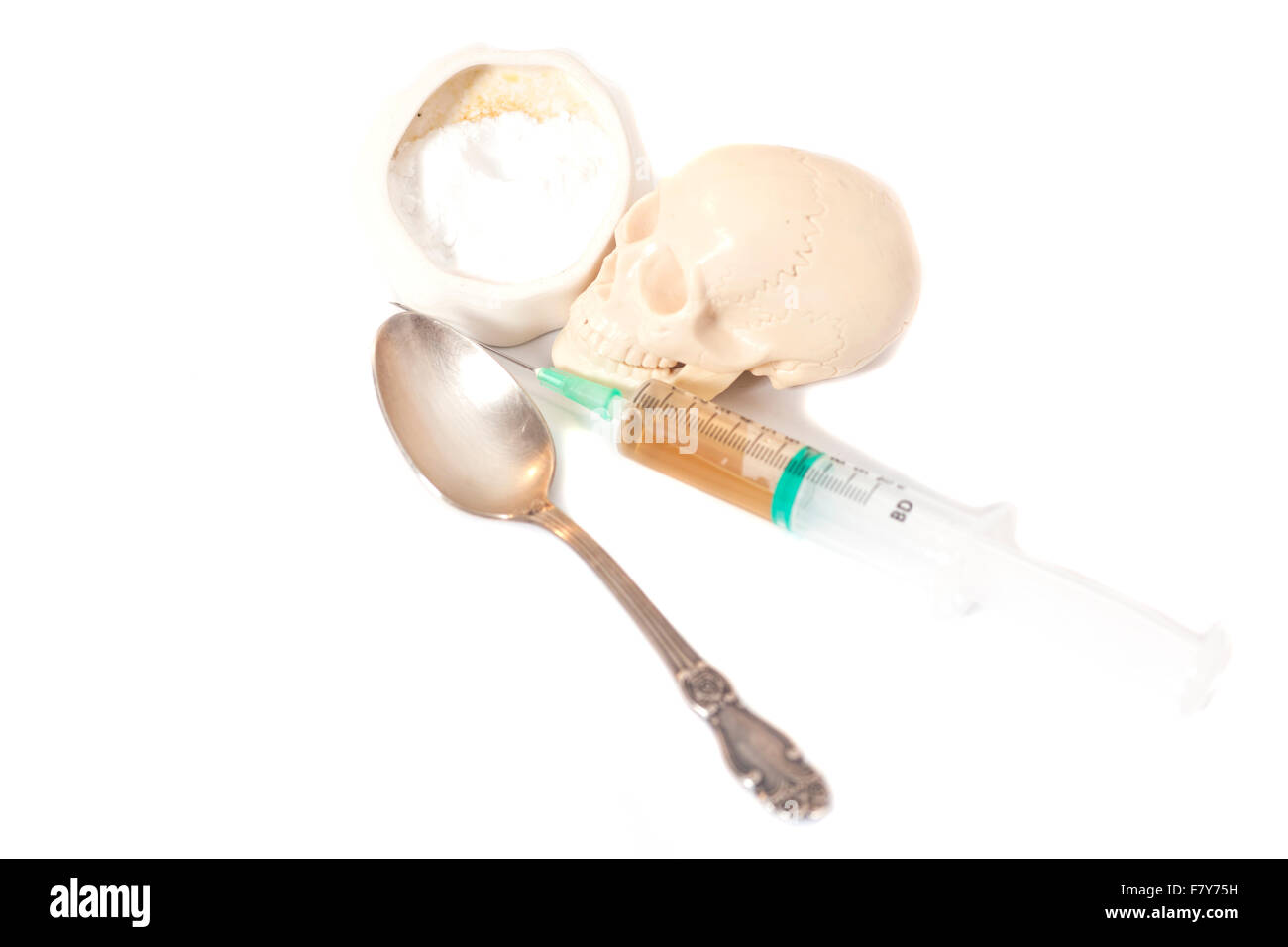Il cranio e la siringa con liquido,cucchiaio e polvere bianca (eroina). Isolato su bianco Foto Stock