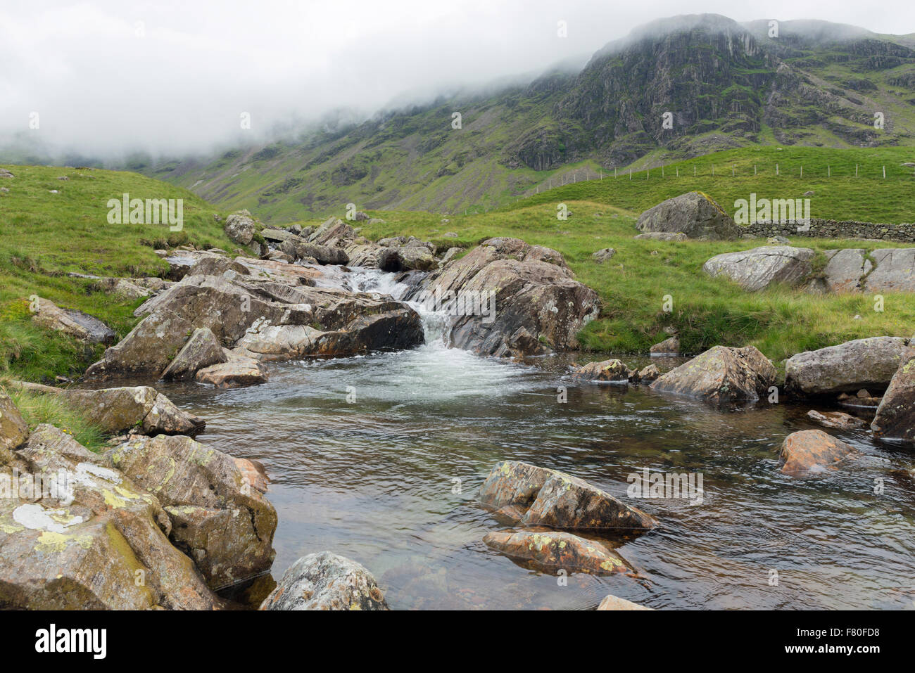 Il Cloud rotoli sopra le scogliere come latte acido Gill fa il suo modo di Saethwaite in Cumbria il Lake District Foto Stock