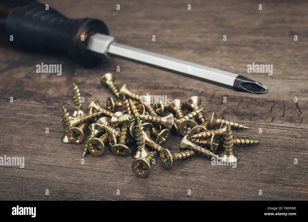 Cacciavite e viti su sfondo di legno Foto Stock
