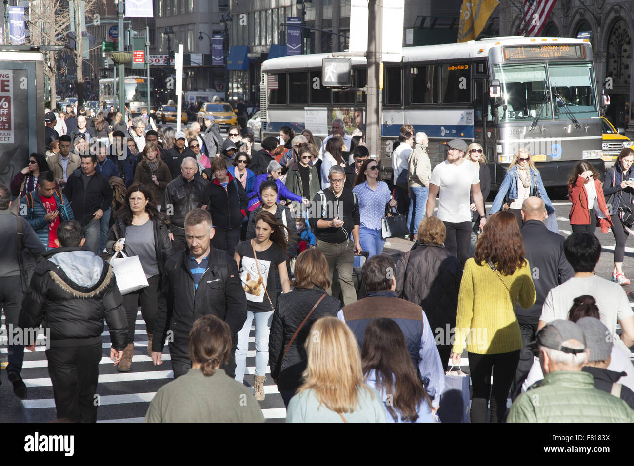 La folla di turisti e amanti dello shopping cross 42nd St. a 5th Ave. sul Venerdì nero all'avvio ufficiale della vacanza stagione di shopping NYC Foto Stock