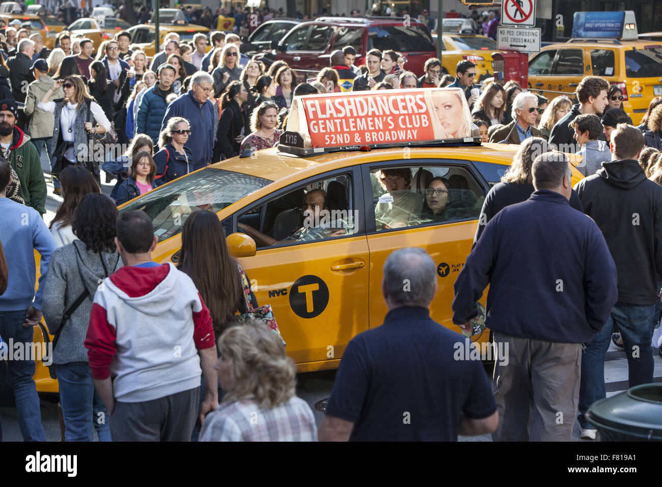 Taxi catturati nel crosswalk circondato da schiere di pedoni che attraversano la strada a Venerdì nero sulla 5 Ave. NYC Foto Stock