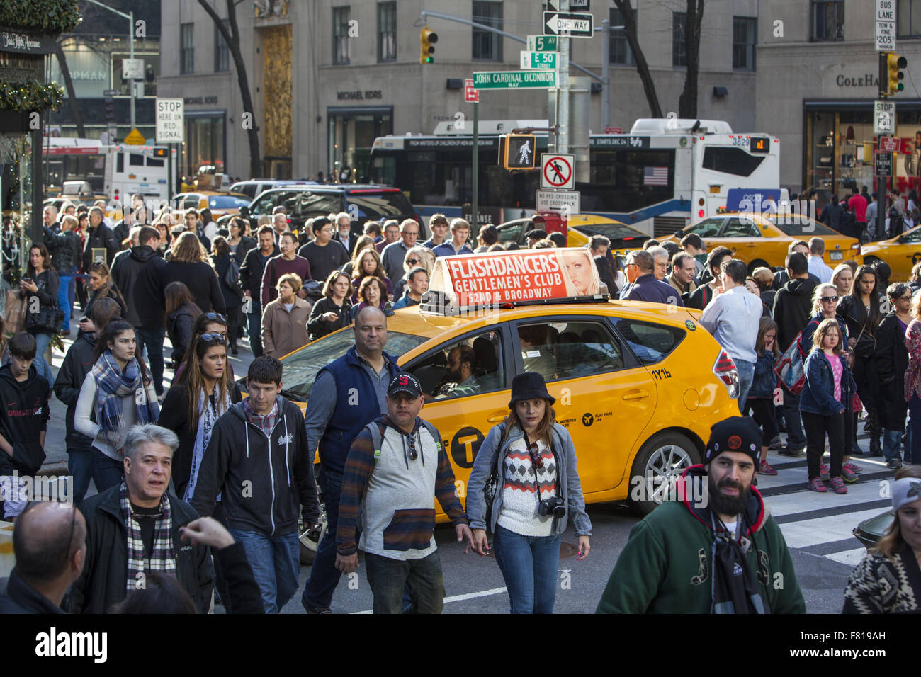 Taxi catturati nel crosswalk circondato da schiere di pedoni che attraversano la strada a Venerdì nero sulla 5 Ave. NYC Foto Stock