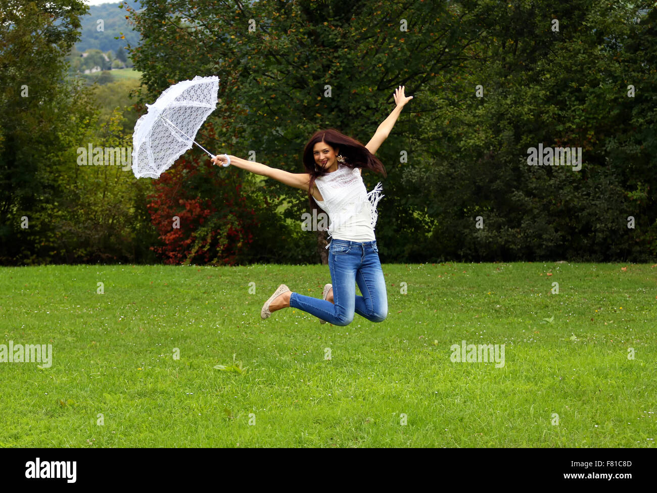 Jumping happy donna con pizzo bianco ombrello. Foto Stock