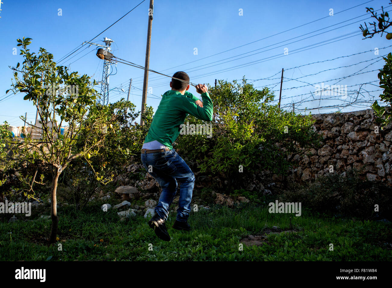 Vicino a Ramallah in Cisgiordania, Medio Oriente. 4 dicembre, 2015. Un giovane palestinese scaglia una roccia da una fionda verso i soldati israeliani vicino a Ramallah in Cisgiordania Credito: Rey T. Byhre/Alamy Live News Foto Stock