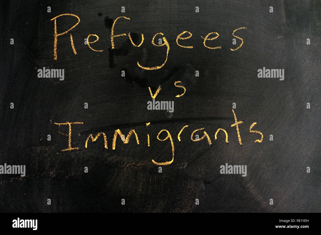 I rifugiati vs immigrati scritti su una lavagna in gesso. Foto Stock