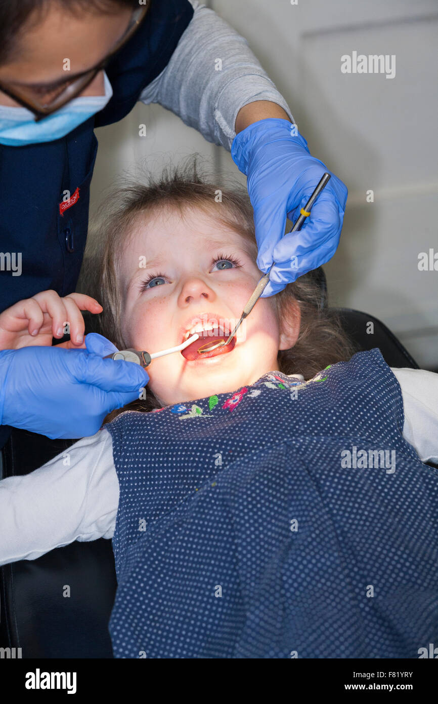 Leggermente ansiose Ragazza 3 anni / tre anni di bambino durante il check up con il dentista per bambini / bambini pratica dentale. Regno Unito Foto Stock