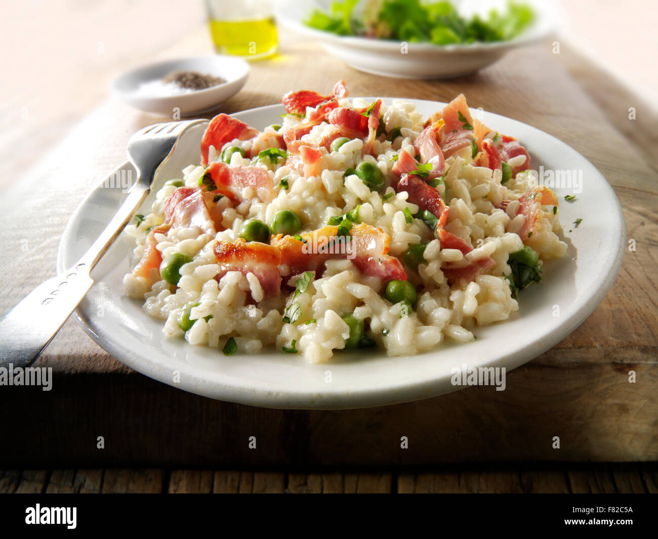 Risotto, piselli e pancetta appena cotti, in un ambiente da tavola Foto Stock