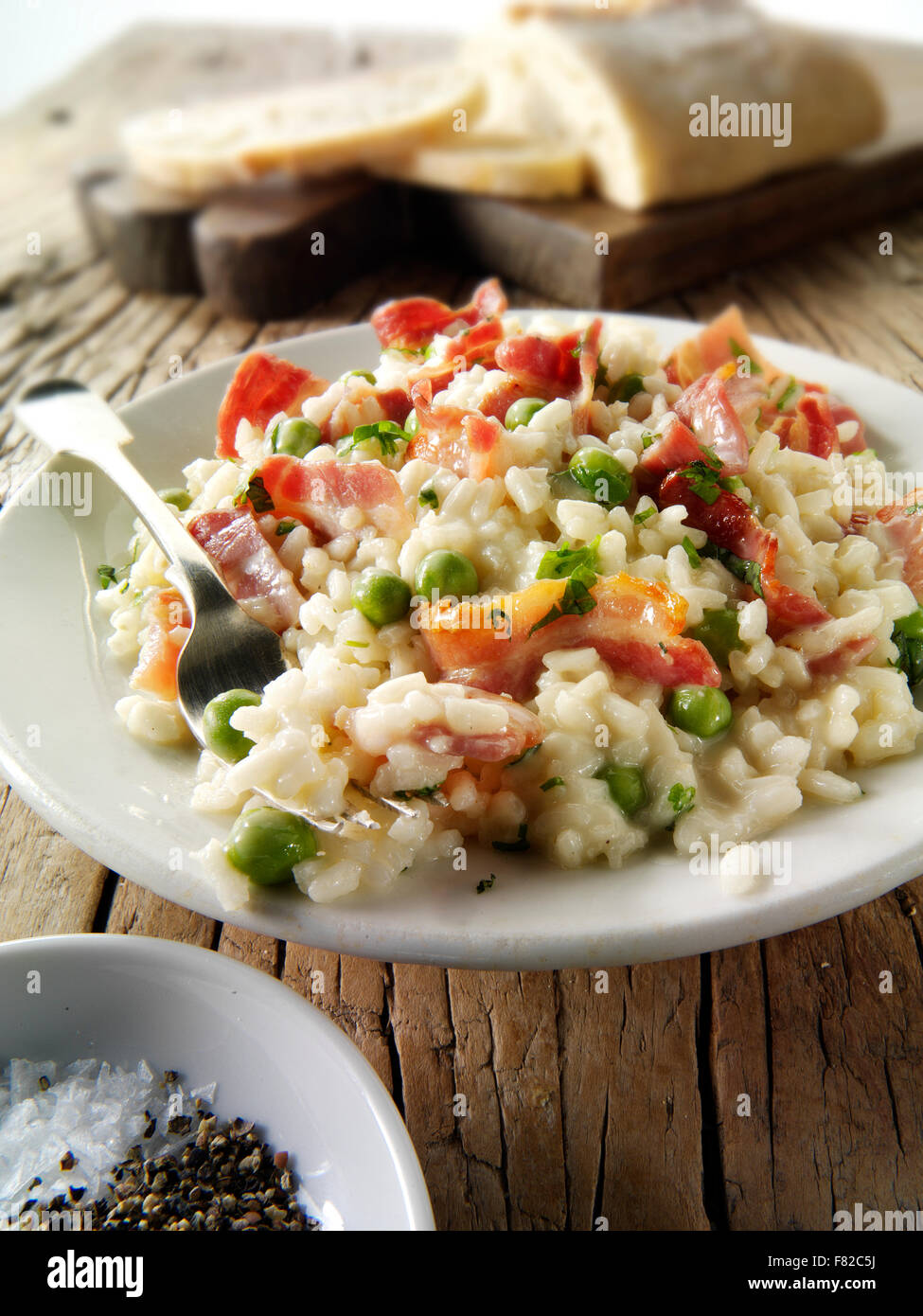 Risotto, piselli e pancetta appena cotti, in un ambiente da tavola Foto Stock