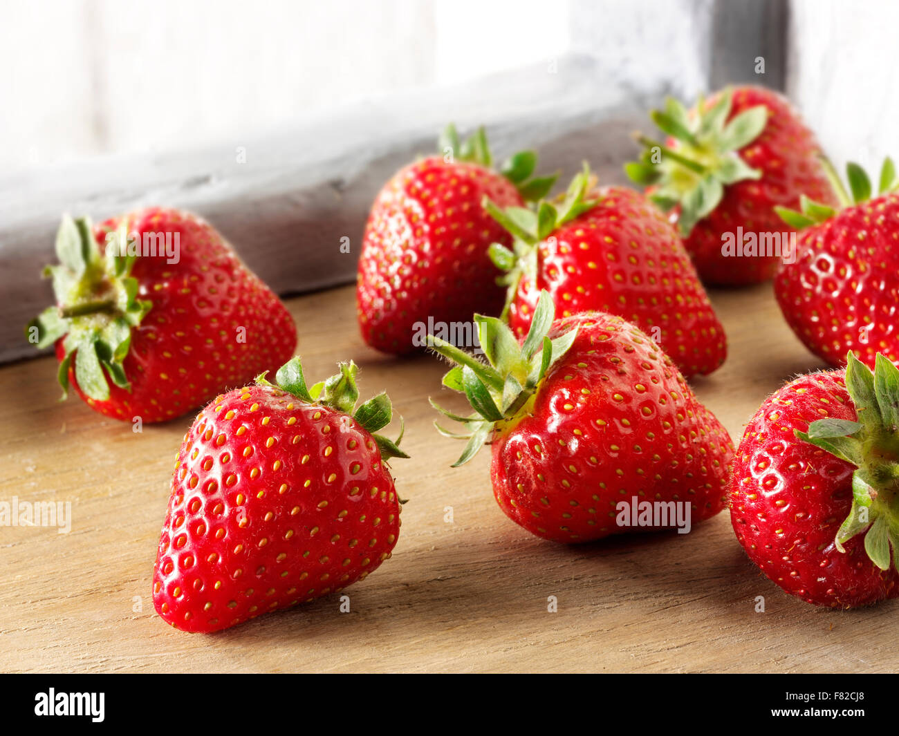 Fresca frutta fragola con scafi di colore verde in una impostazione di cucina Foto Stock