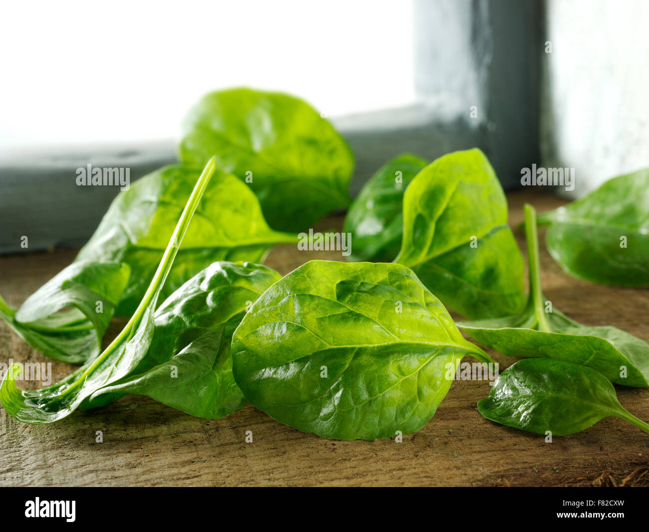 Primo piano di foglie di spinaci fresche non cotte in un ambiente rustico Foto Stock