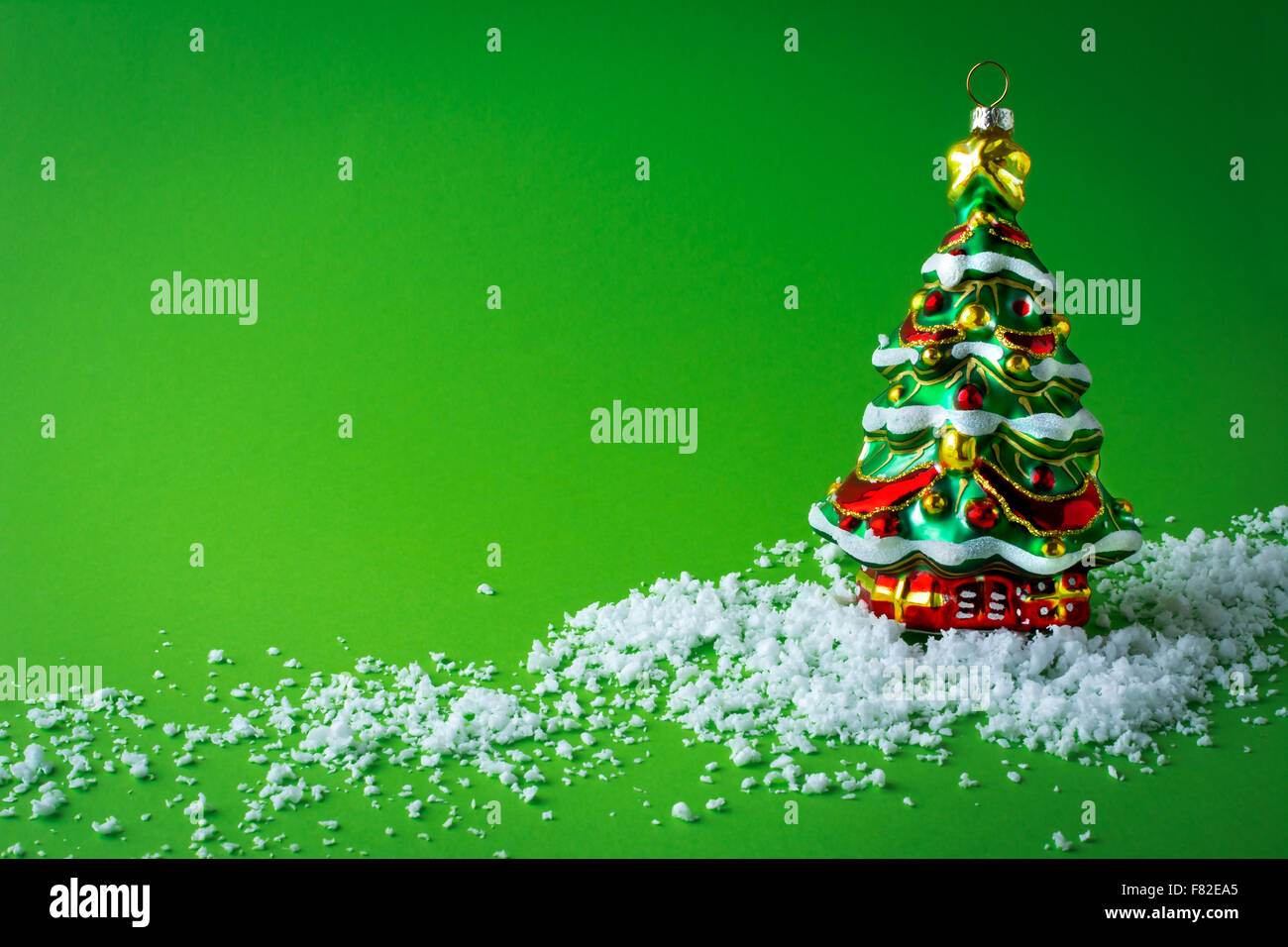 Decorazione per albero di Natale albero di natale nella neve su uno sfondo verde Foto Stock