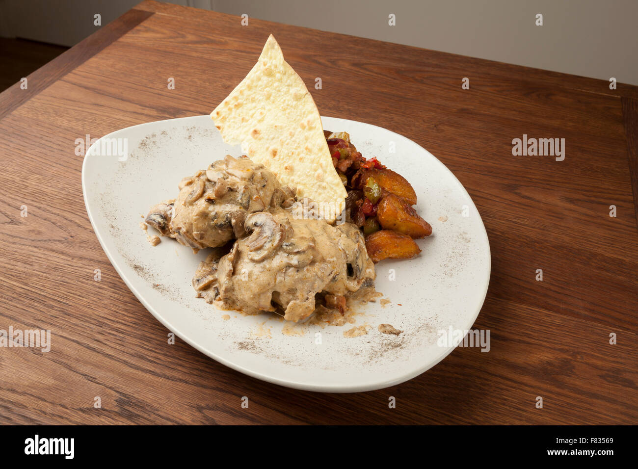 La carne di maiale in salsa di funghi con patate al forno sul tavolo di legno Foto Stock