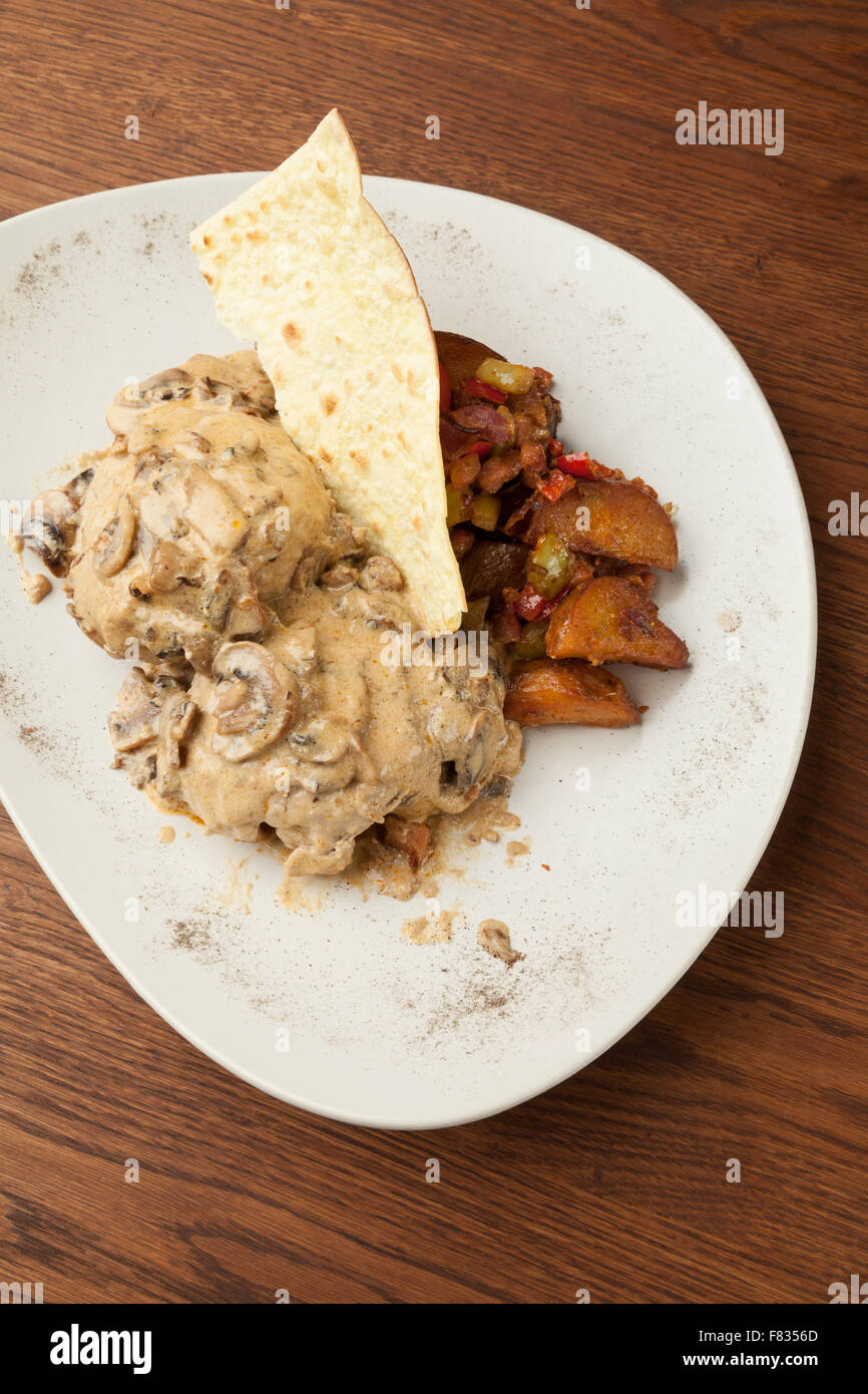 La carne di maiale in salsa di funghi con patate al forno sul tavolo di legno Foto Stock