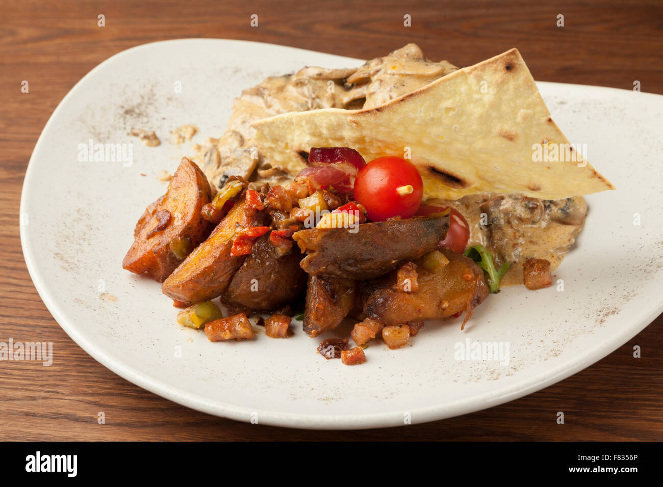 La carne di maiale in salsa di funghi con patate al forno sul tavolo di legno Foto Stock
