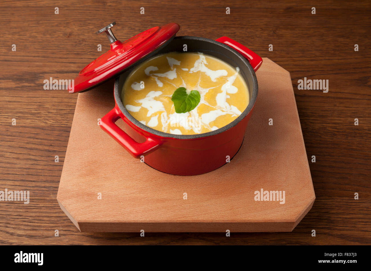 Zuppa di pollo in una ciotola rossa sul piatto di legno Foto Stock