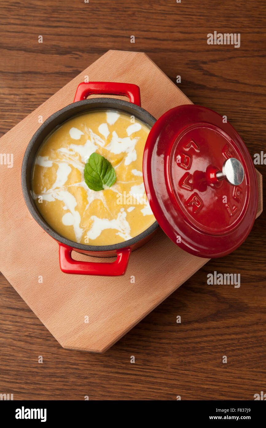 Zuppa di pollo in una ciotola rossa sul piatto di legno Foto Stock