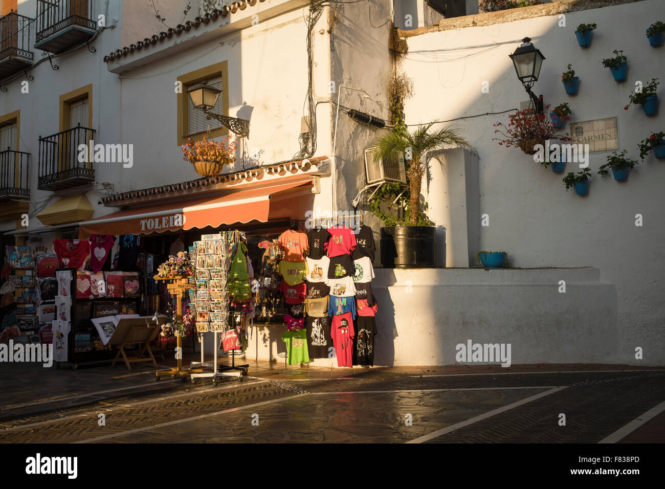 Splendidamente illuminato strada spagnolo con un negozio di souvenir e vasi di fiori sulla parete con gerani accanto ad un lampione Foto Stock