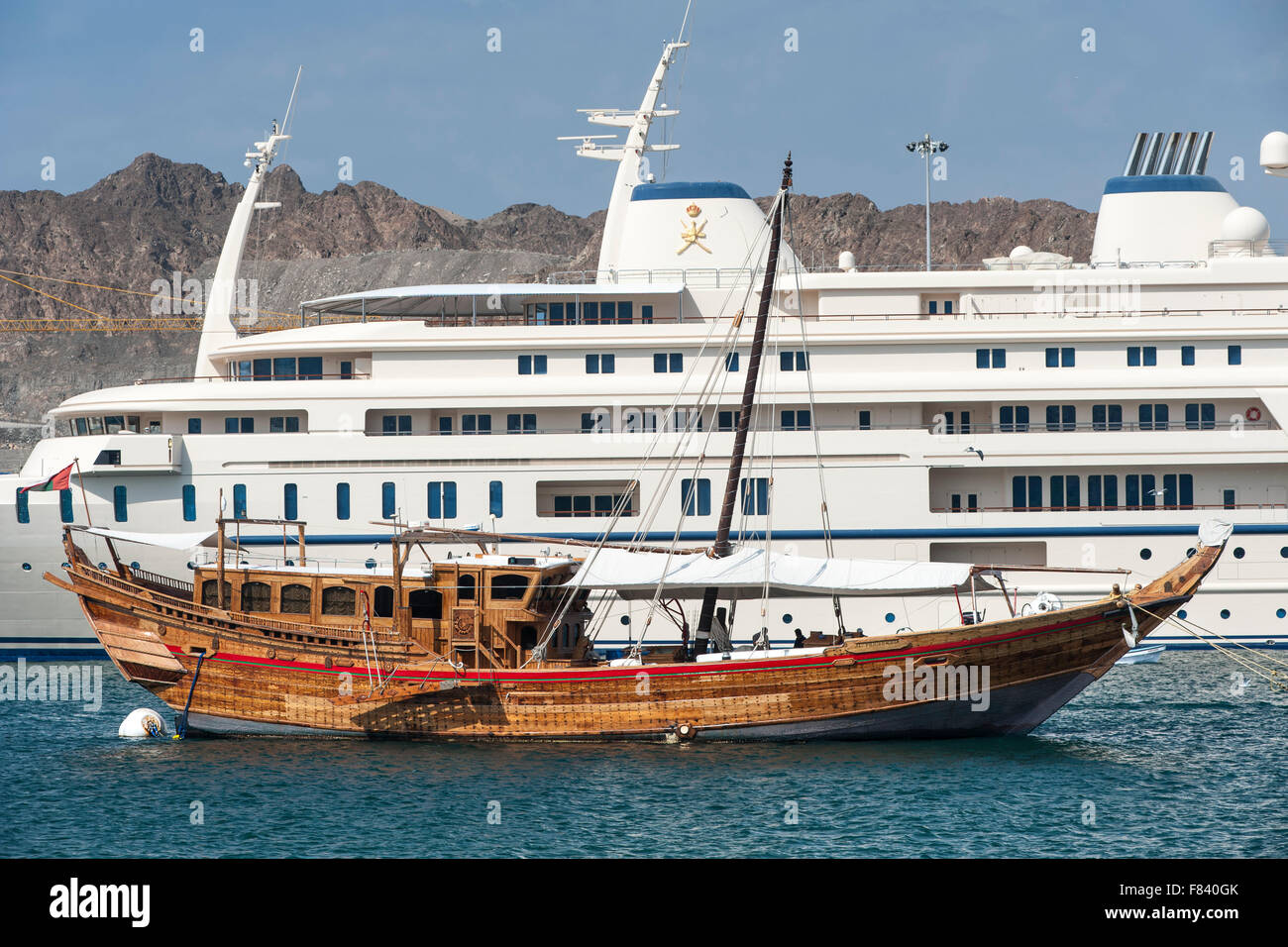 La barca di legno ormeggiata lungo i super yacht del sultano di Oman in Mutrah Harbour, Muscat. Foto Stock