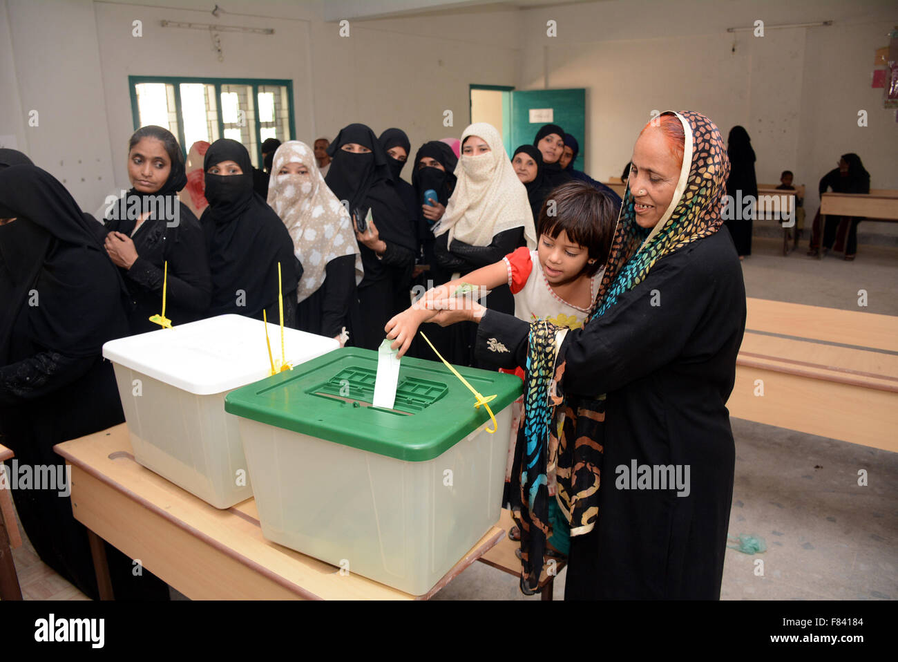 Karachi. 5 Dic, 2015. Un bambino pakistano esprime un voto per una donna ad un seggio elettorale durante le elezioni dei governo locali nel Sud del Pakistan città portuale di Karachi su dicembre 5, 2015. Credito: Masroor/Xinhua/Alamy Live News Foto Stock