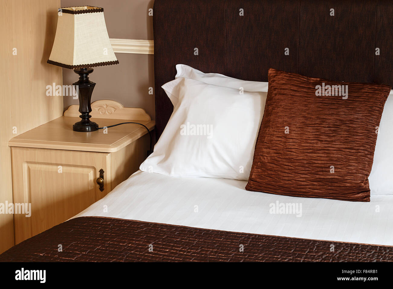 Bed and breakfast camera generico con dettaglio del letto, fogli e un comodino grande per qualsiasi guest house. Foto Stock