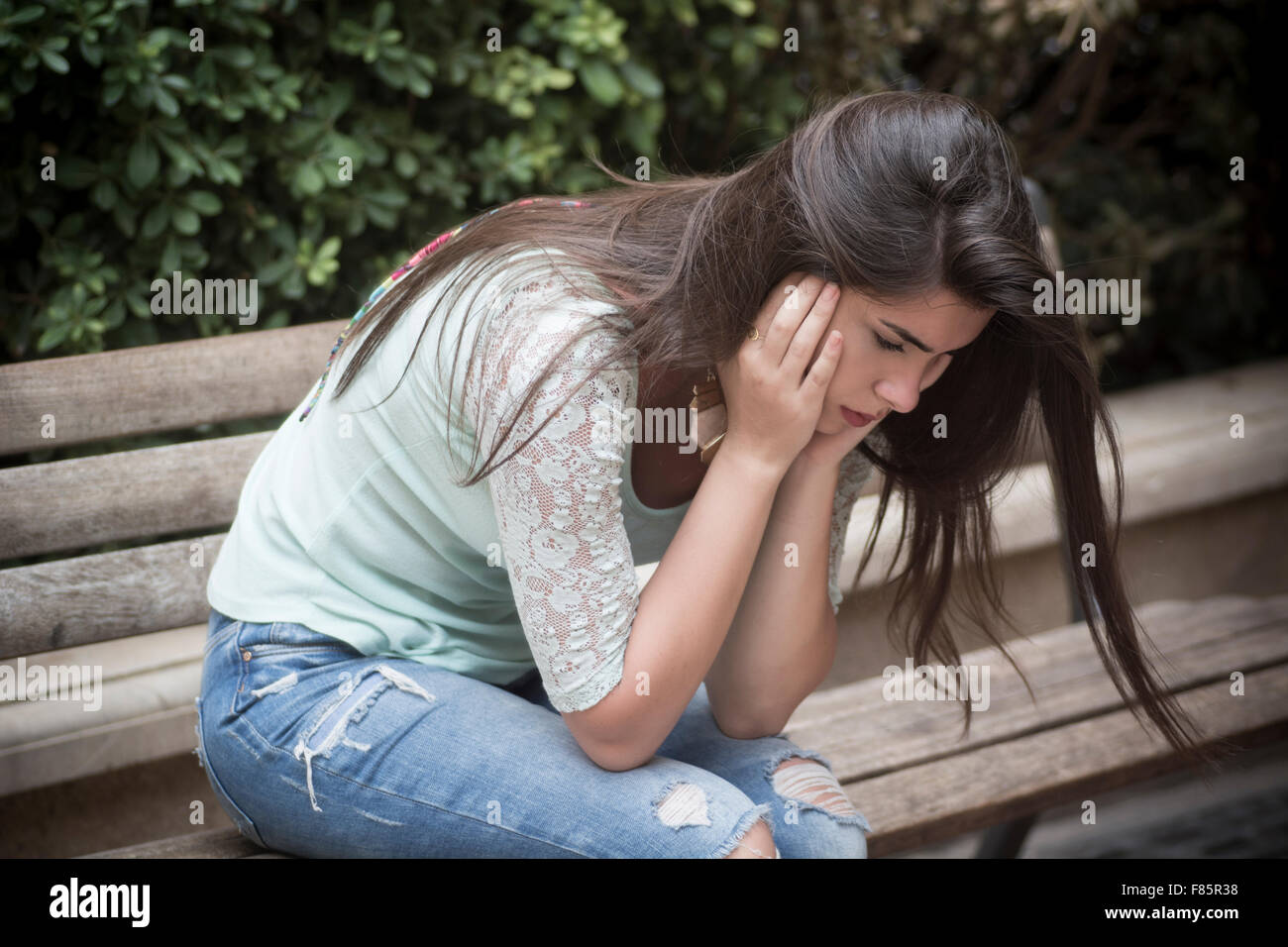 Sottolineato giovane donna si sedette sul banco in testa le mani Foto Stock