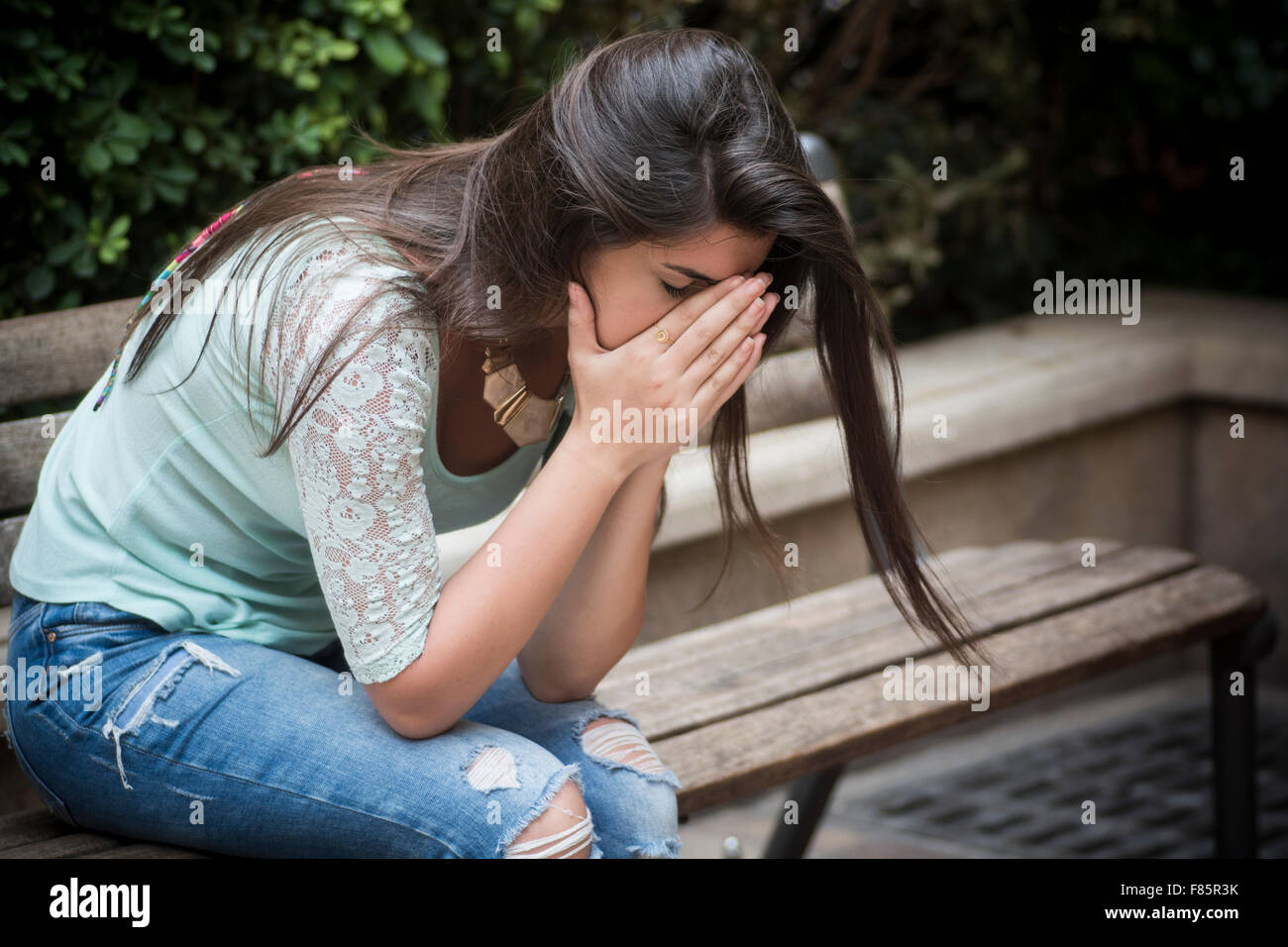 Sottolineato giovane donna si sedette sul banco in testa le mani Foto Stock