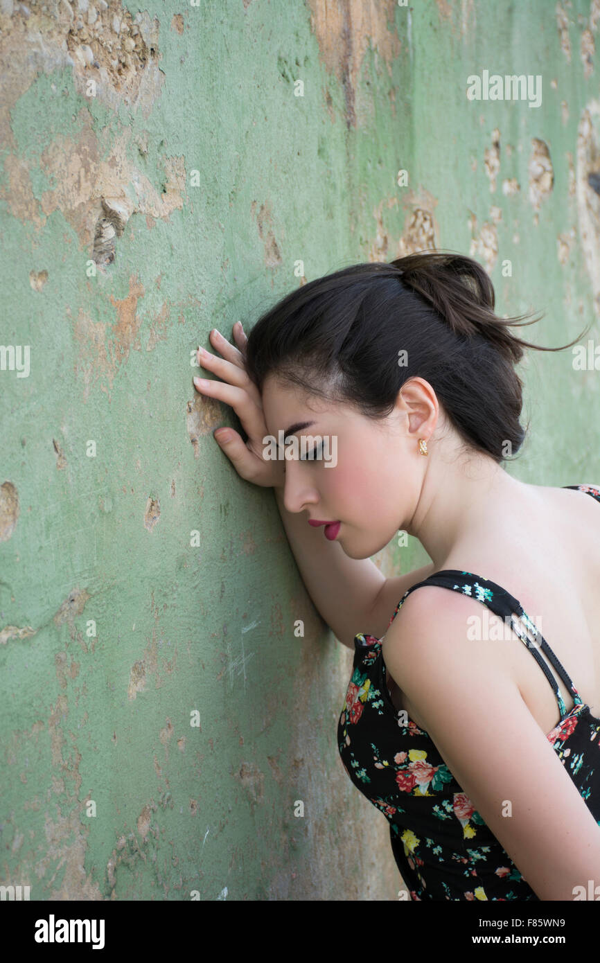 Triste giovane donna appoggiata contro il muro Foto Stock