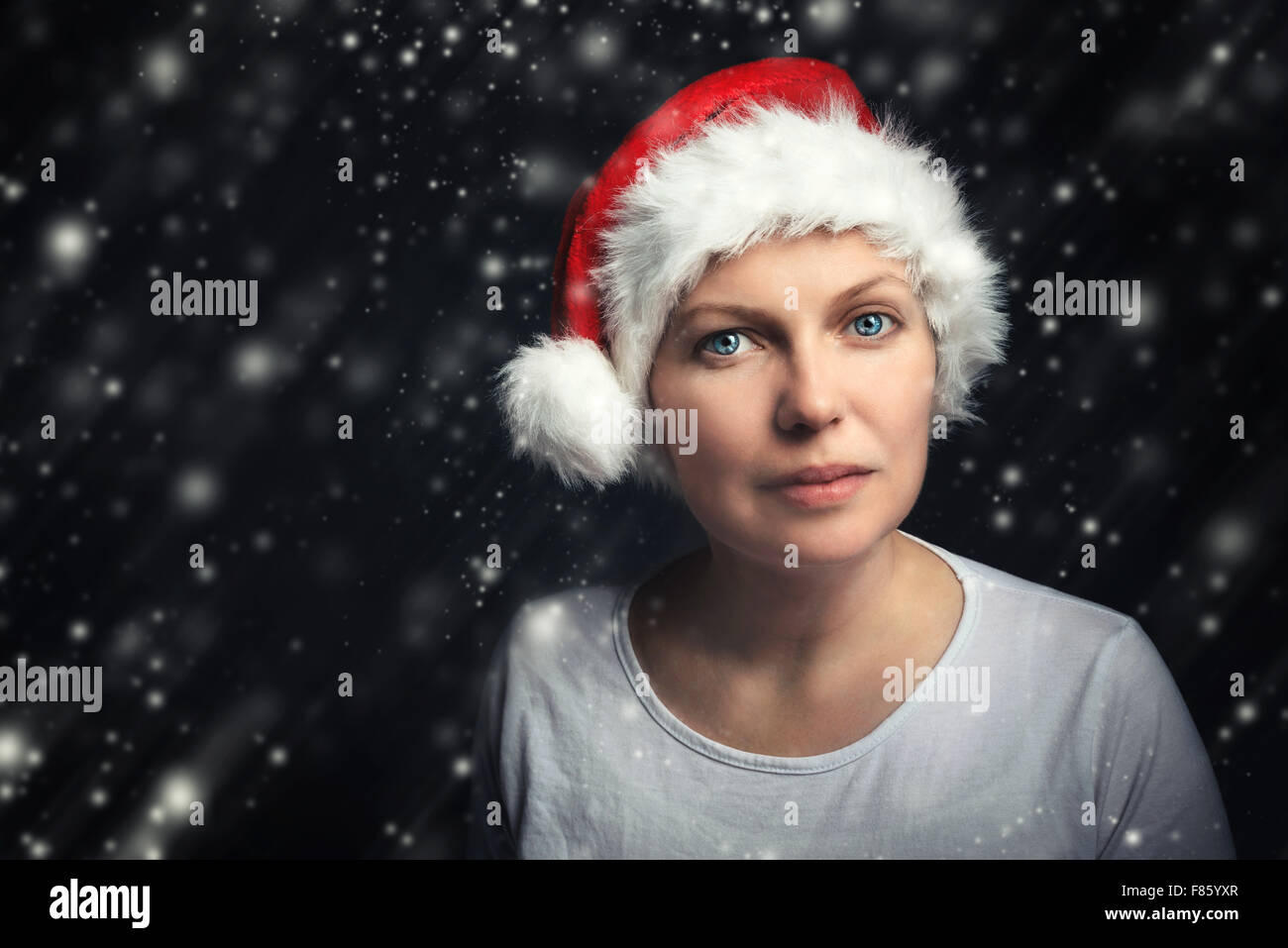 Natale bellezza femminile ritratto con i fiocchi di neve, bella donna adulta con gli occhi blu che indossa Santa Claus hat e guardando a ca Foto Stock