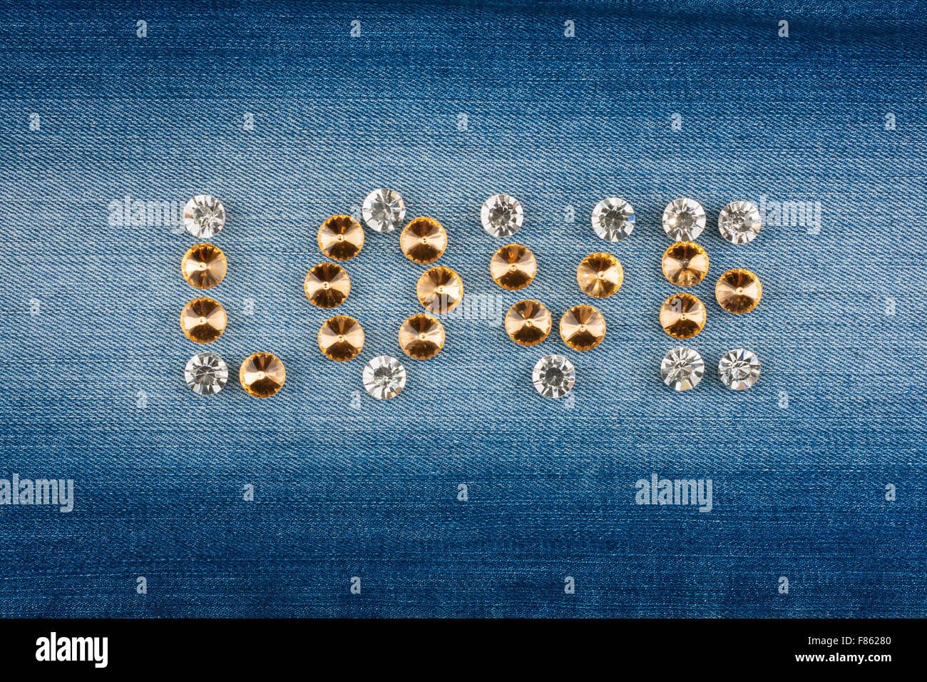 La parola amore fatto di strass sul tessuto denim, come sfondo, tessitura Foto Stock