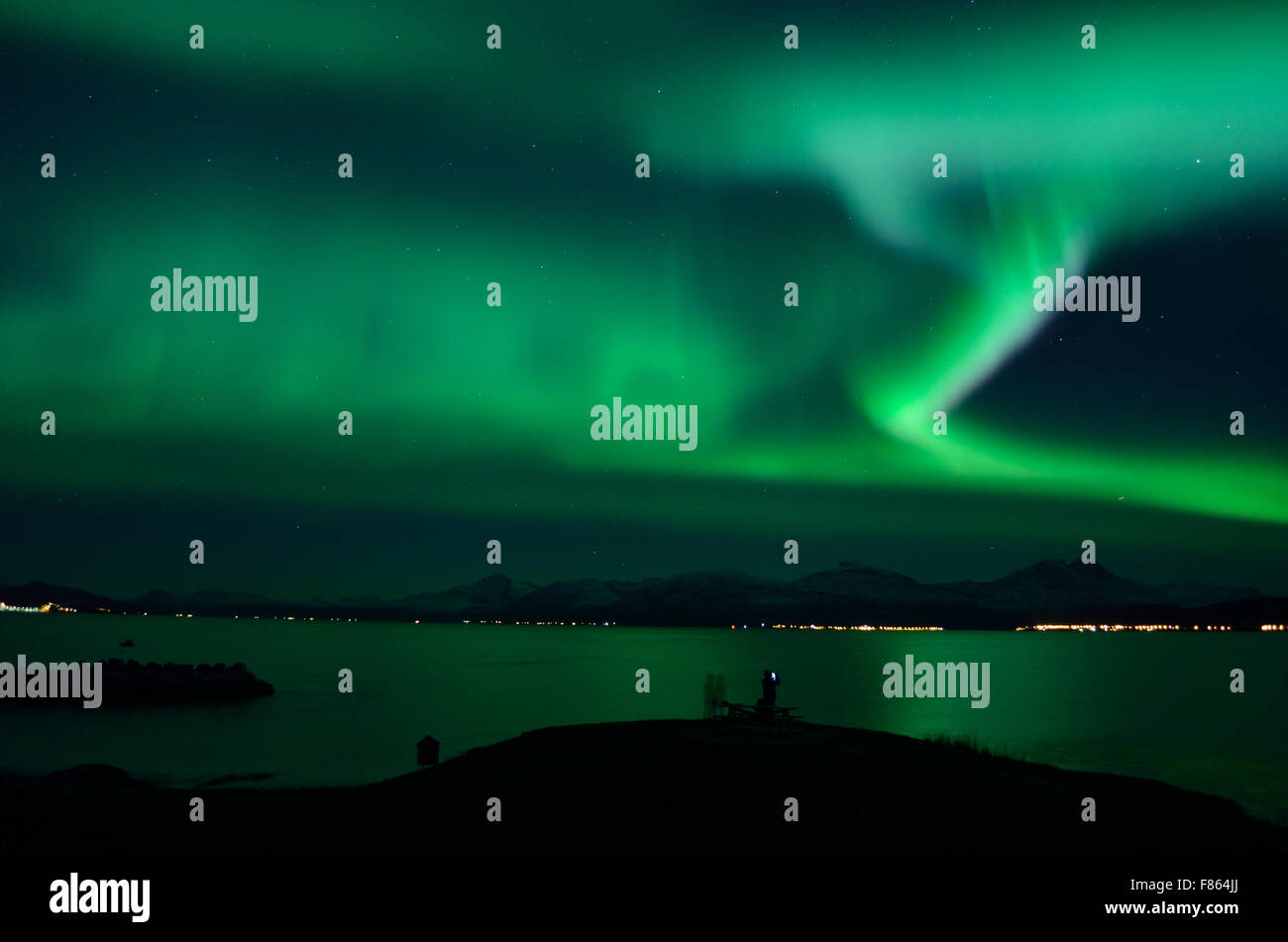 Forte aurora boreale sul fiordo e montagna con il turista nella parte anteriore Foto Stock
