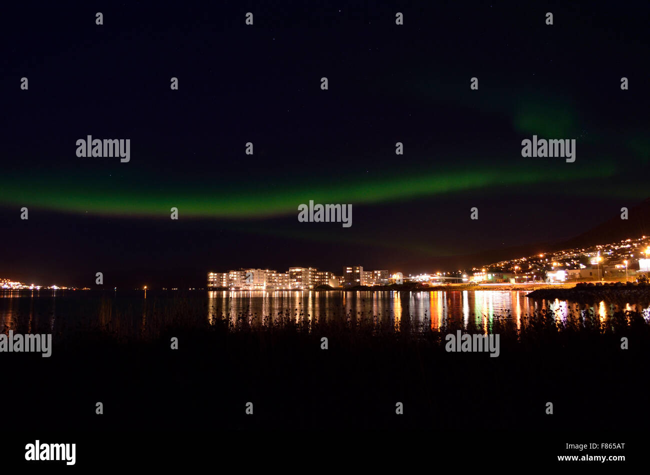 Aurora boreale e città il riflesso della luce sulla superficie di un fiordo in autunno Foto Stock
